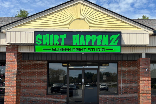 Storefront with 'Shirt Happens sign on a clear day